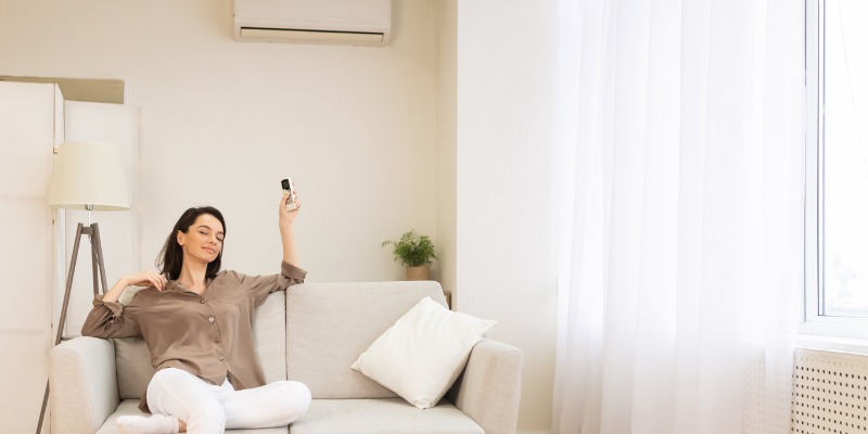 Woman sitting on couch turning on air conditioning