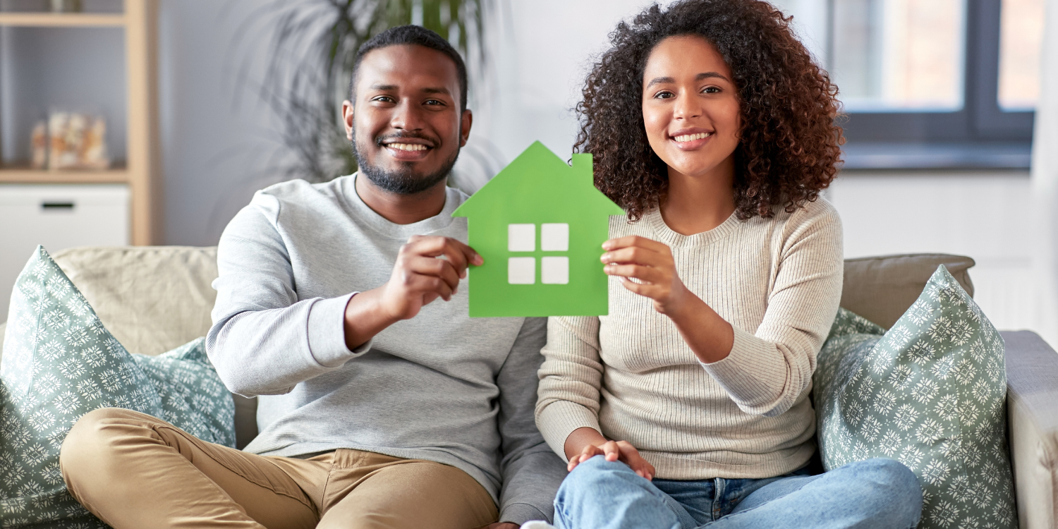 Couple sitting on couch holding Green home for Greener Homes concept photo - What is the Greener Homes Loan, and Am I Eligible?